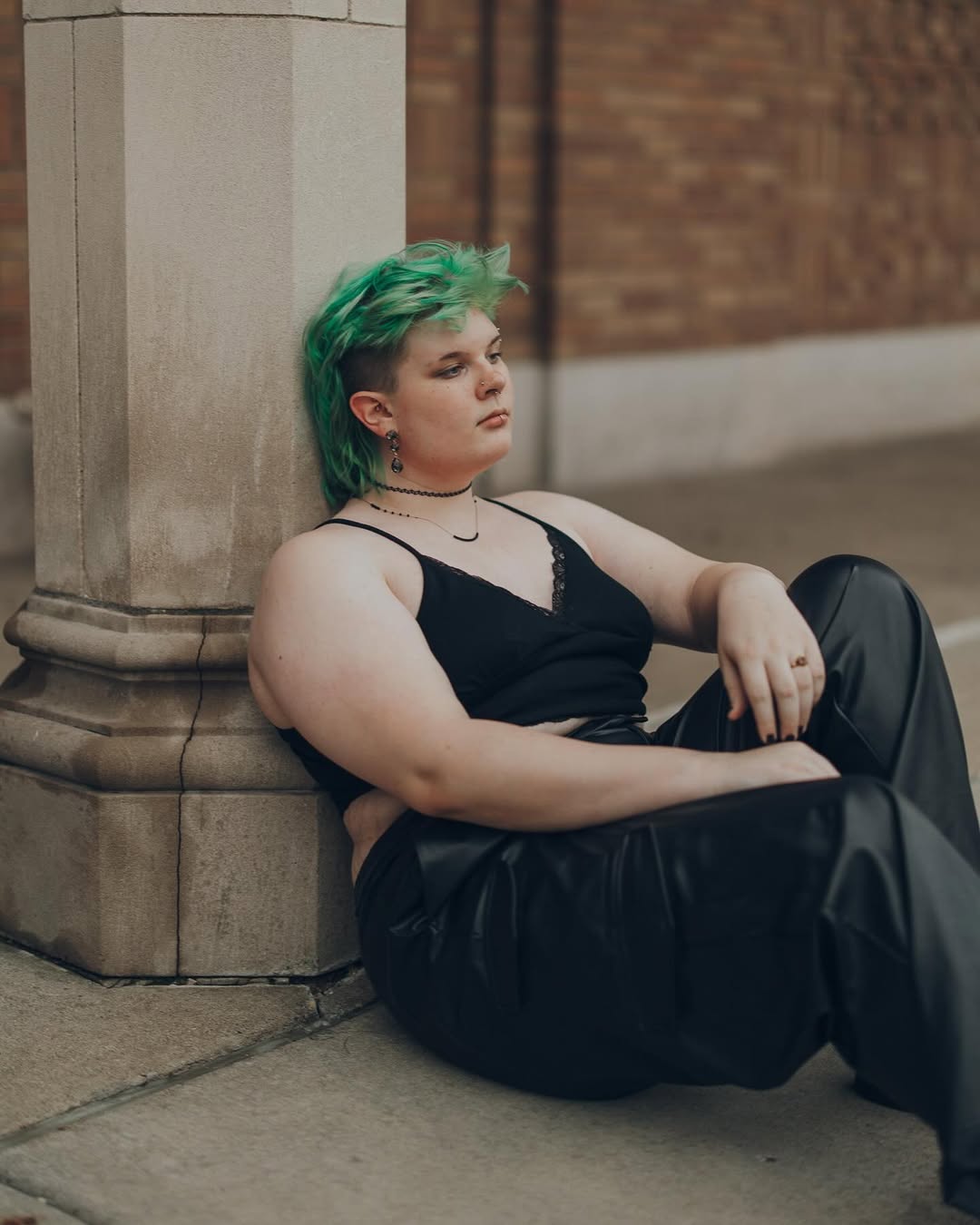 photo of amara without the cardigan, sitting against a pillar